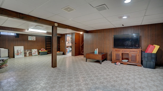 living room with a paneled ceiling and wooden walls