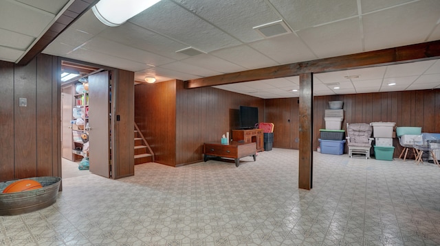 basement with wooden walls and a drop ceiling