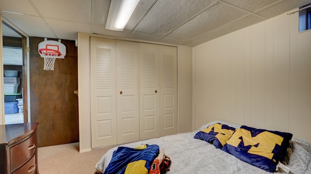 carpeted bedroom featuring a drop ceiling and a closet