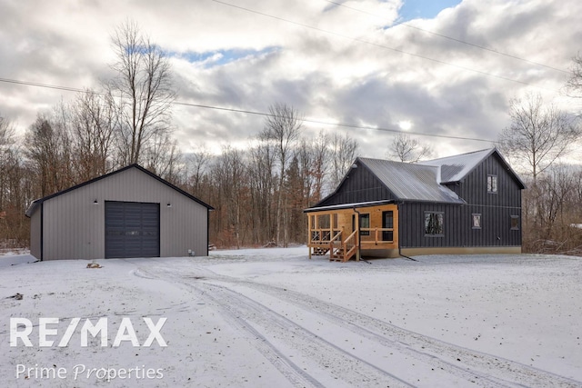 exterior space with covered porch, a garage, and an outbuilding