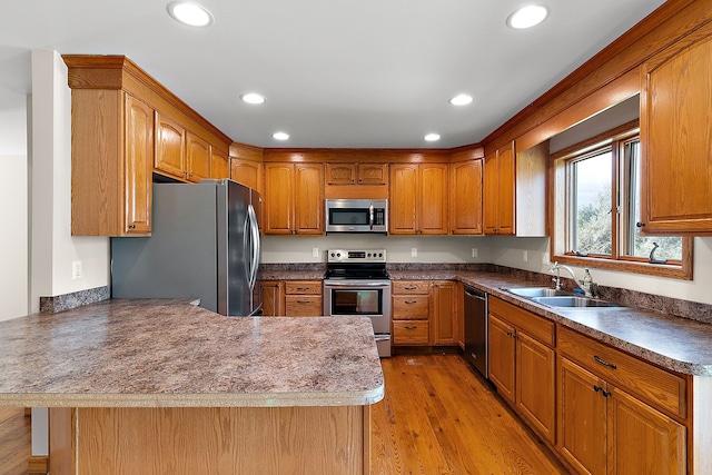 kitchen featuring kitchen peninsula, sink, stainless steel appliances, and light hardwood / wood-style floors