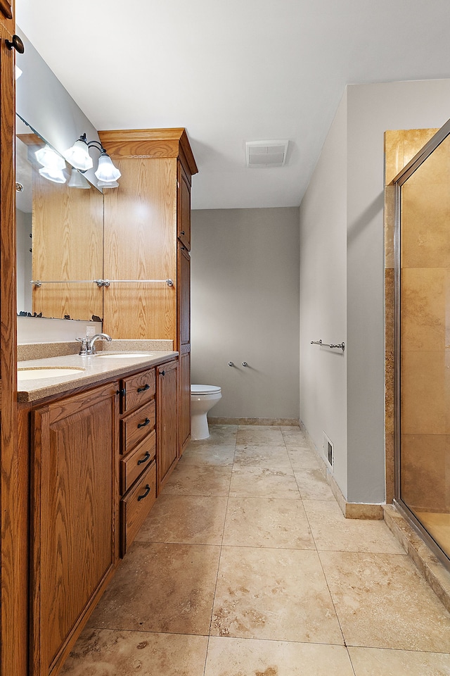 bathroom with tile patterned floors, vanity, toilet, and a shower with door