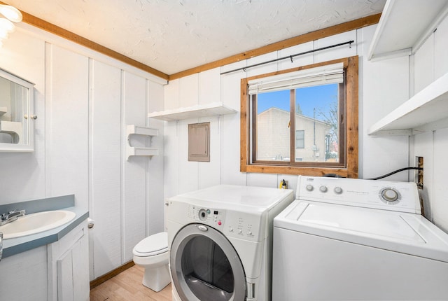 laundry area with sink, light wood-type flooring, and washing machine and clothes dryer