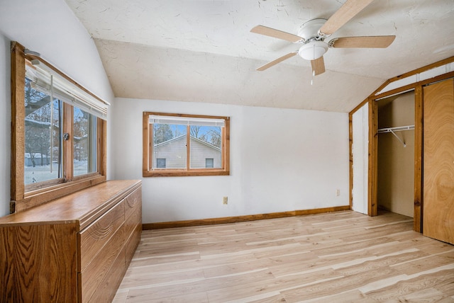 unfurnished bedroom featuring light wood-type flooring, a closet, ceiling fan, and lofted ceiling