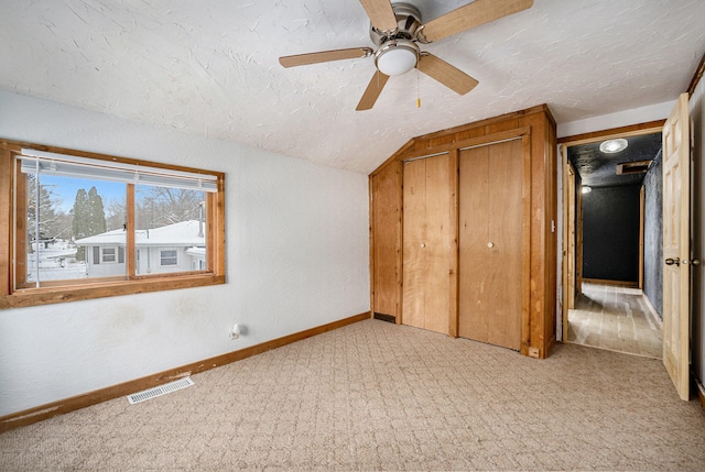 unfurnished bedroom with ceiling fan, a closet, light colored carpet, and vaulted ceiling