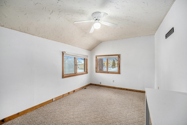 spare room featuring lofted ceiling, ceiling fan, carpet floors, and a textured ceiling