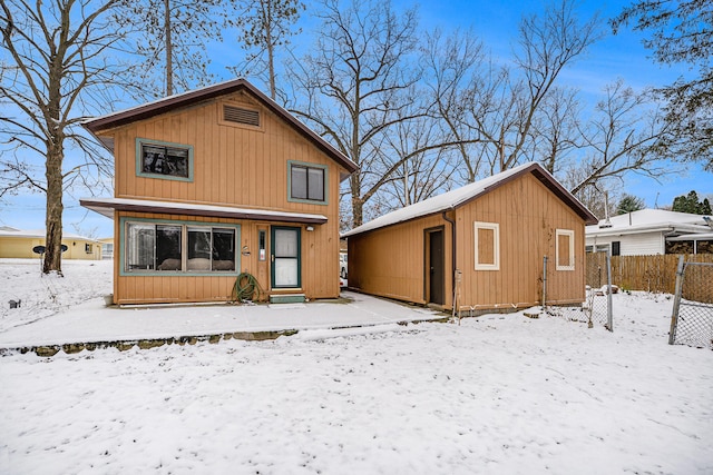 snow covered back of property with an outdoor structure