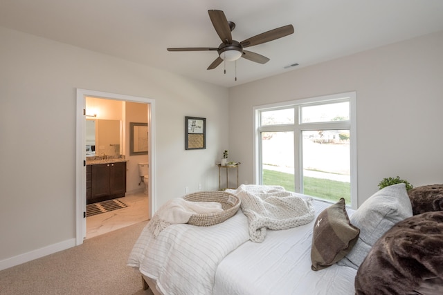 bedroom with light carpet, ensuite bath, and ceiling fan