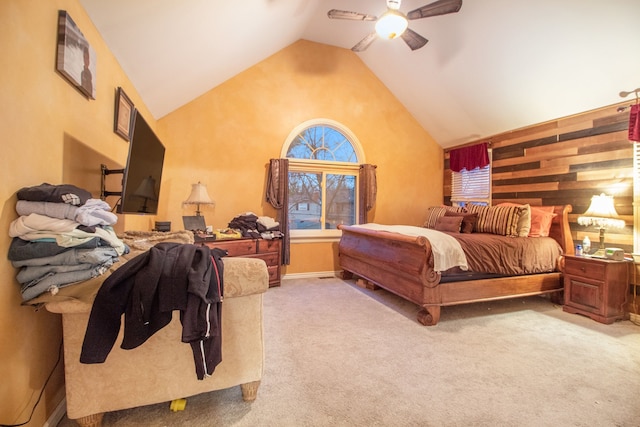 carpeted bedroom with high vaulted ceiling, ceiling fan, and wood walls