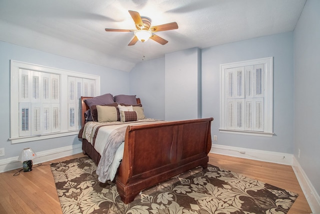 bedroom with hardwood / wood-style floors, ceiling fan, a textured ceiling, and vaulted ceiling