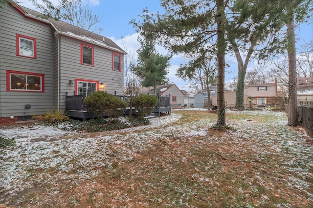 yard layered in snow featuring a trampoline and a wooden deck