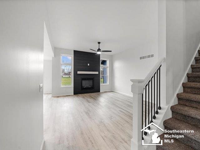 unfurnished living room featuring hardwood / wood-style floors, ceiling fan, and a fireplace