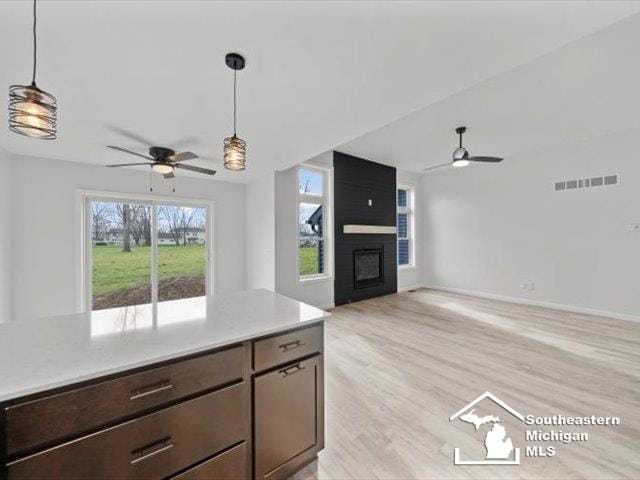 kitchen featuring a fireplace, dark brown cabinets, light hardwood / wood-style flooring, and hanging light fixtures