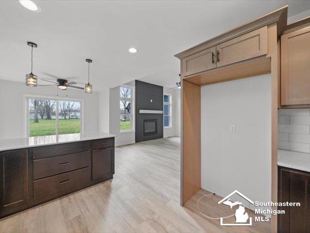 kitchen with backsplash, ceiling fan, a fireplace, and light hardwood / wood-style flooring