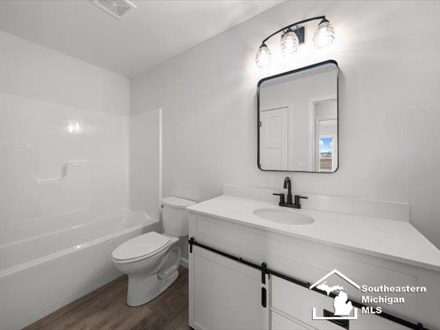 full bathroom with wood-type flooring, vanity, bathing tub / shower combination, and toilet