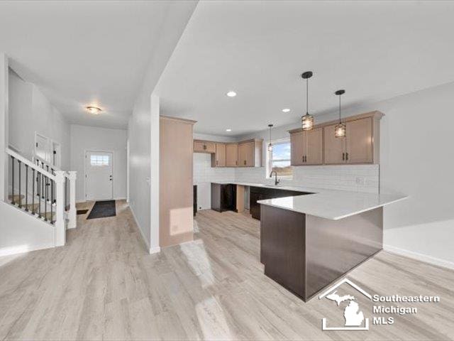 kitchen with light hardwood / wood-style floors, kitchen peninsula, backsplash, and hanging light fixtures