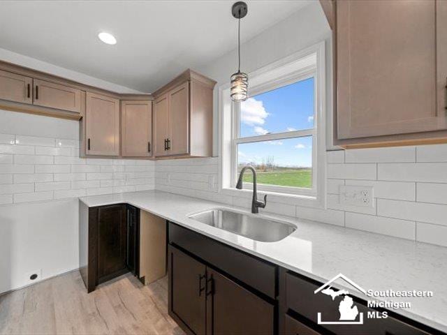 kitchen featuring backsplash, light hardwood / wood-style flooring, hanging light fixtures, and sink