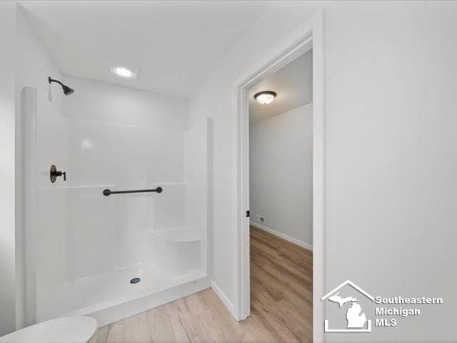 bathroom with a shower, wood-type flooring, and toilet