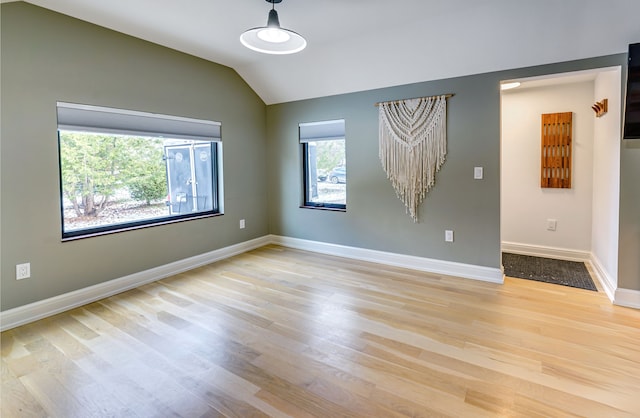 spare room featuring lofted ceiling and light wood-type flooring