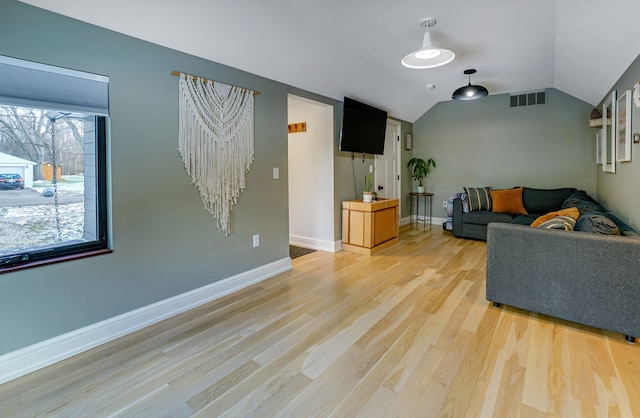 living room with light hardwood / wood-style floors and vaulted ceiling