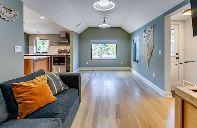 living room featuring light wood-type flooring, vaulted ceiling, and sink