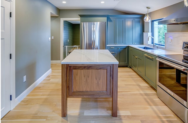 kitchen with light stone countertops, stainless steel appliances, extractor fan, sink, and hanging light fixtures