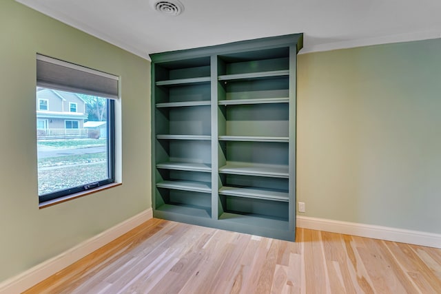 unfurnished room with hardwood / wood-style flooring and crown molding