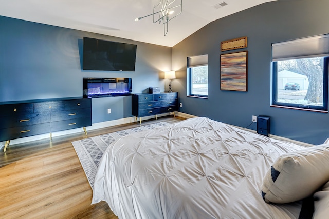 bedroom featuring wood-type flooring, an inviting chandelier, and vaulted ceiling