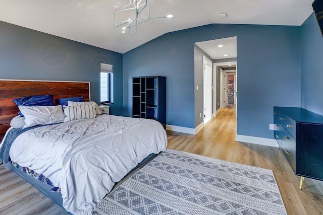 bedroom with a chandelier, vaulted ceiling, and light hardwood / wood-style flooring