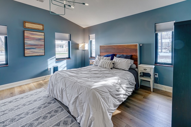 bedroom with hardwood / wood-style flooring, vaulted ceiling, and multiple windows