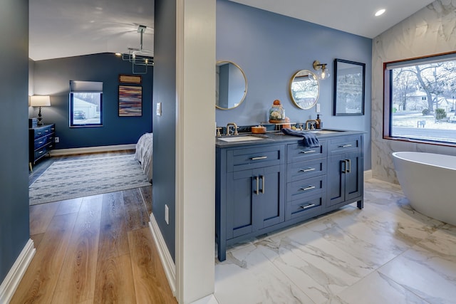 bathroom featuring a tub to relax in, hardwood / wood-style floors, vanity, and vaulted ceiling