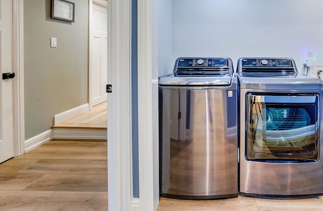 laundry area with washing machine and dryer and light hardwood / wood-style floors