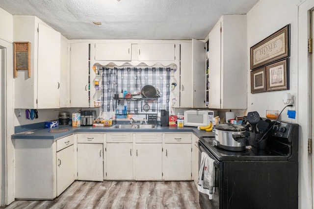 kitchen with a textured ceiling, light wood-type flooring, black electric range oven, and sink