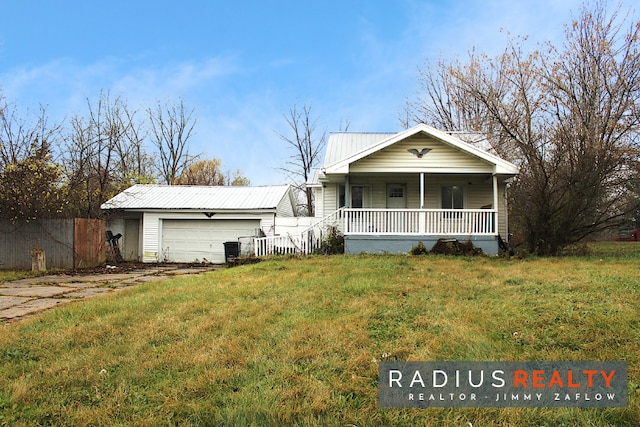 view of front of house with an outbuilding, covered porch, a front yard, and a garage