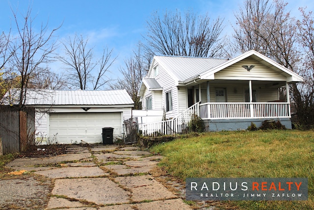 view of front of property featuring covered porch, a front yard, and a garage