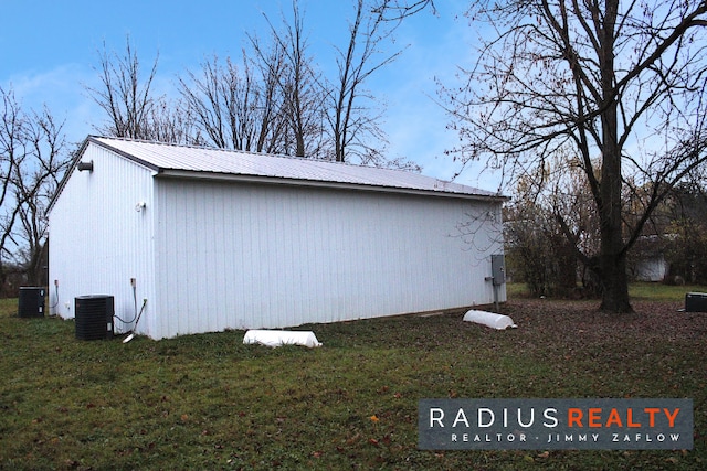 view of side of home with central AC, a yard, and an outdoor structure