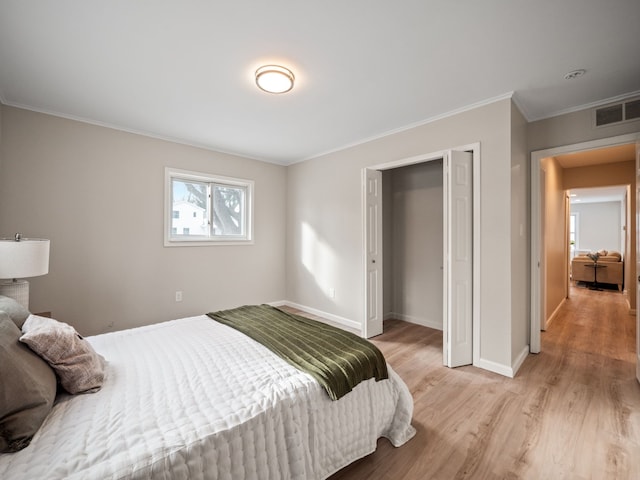 bedroom featuring light wood-type flooring, a closet, and ornamental molding