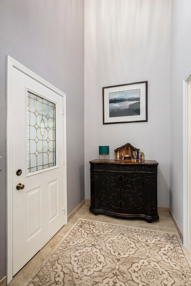 entrance foyer featuring a high ceiling, light tile patterned flooring, and baseboards