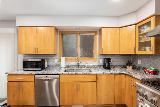 kitchen featuring light stone counters, appliances with stainless steel finishes, tasteful backsplash, and a sink