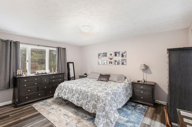 bedroom with baseboards, a textured ceiling, and dark wood-style flooring