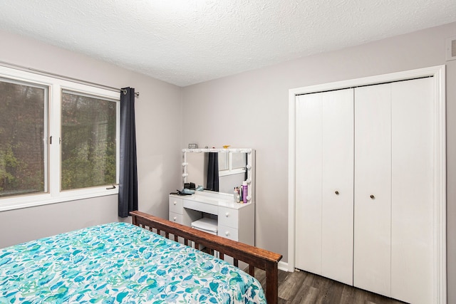 bedroom featuring a closet, a textured ceiling, visible vents, and dark wood-style floors