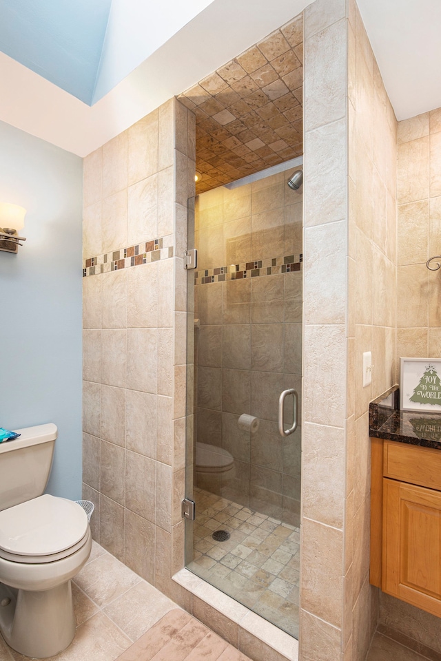 bathroom with vanity, tile patterned floors, toilet, and a stall shower