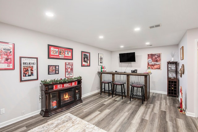 bar with a fireplace and wood-type flooring