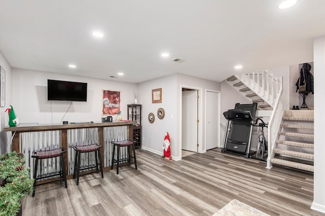 exercise room featuring hardwood / wood-style floors and indoor bar