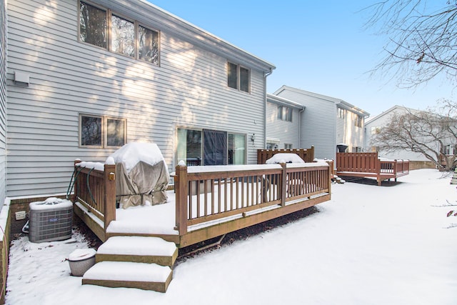 snow covered house featuring central air condition unit and a wooden deck