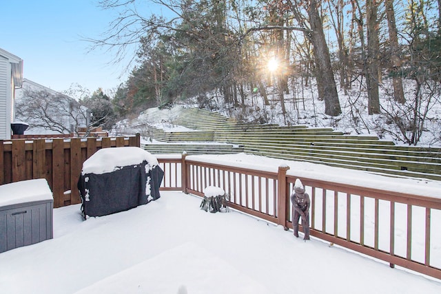 snow covered deck featuring grilling area and fence