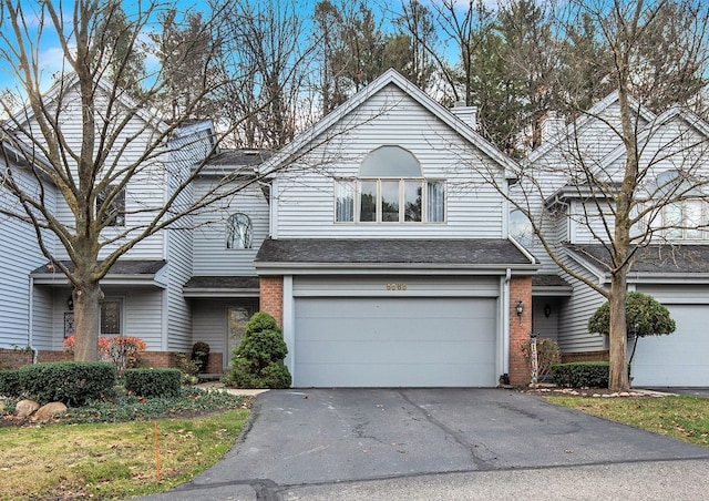 view of front of house featuring brick siding, an attached garage, driveway, and a shingled roof