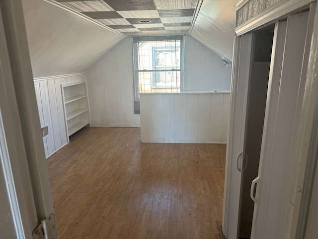 bonus room featuring hardwood / wood-style flooring, wooden walls, and vaulted ceiling