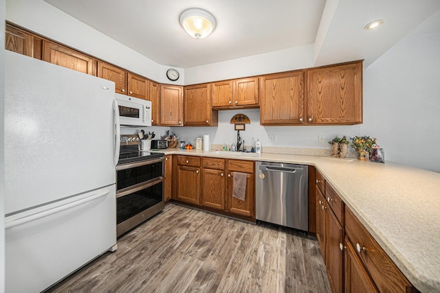 kitchen with appliances with stainless steel finishes, dark hardwood / wood-style flooring, and sink