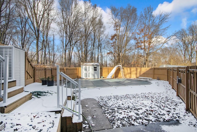 snowy yard with a storage shed and a covered pool